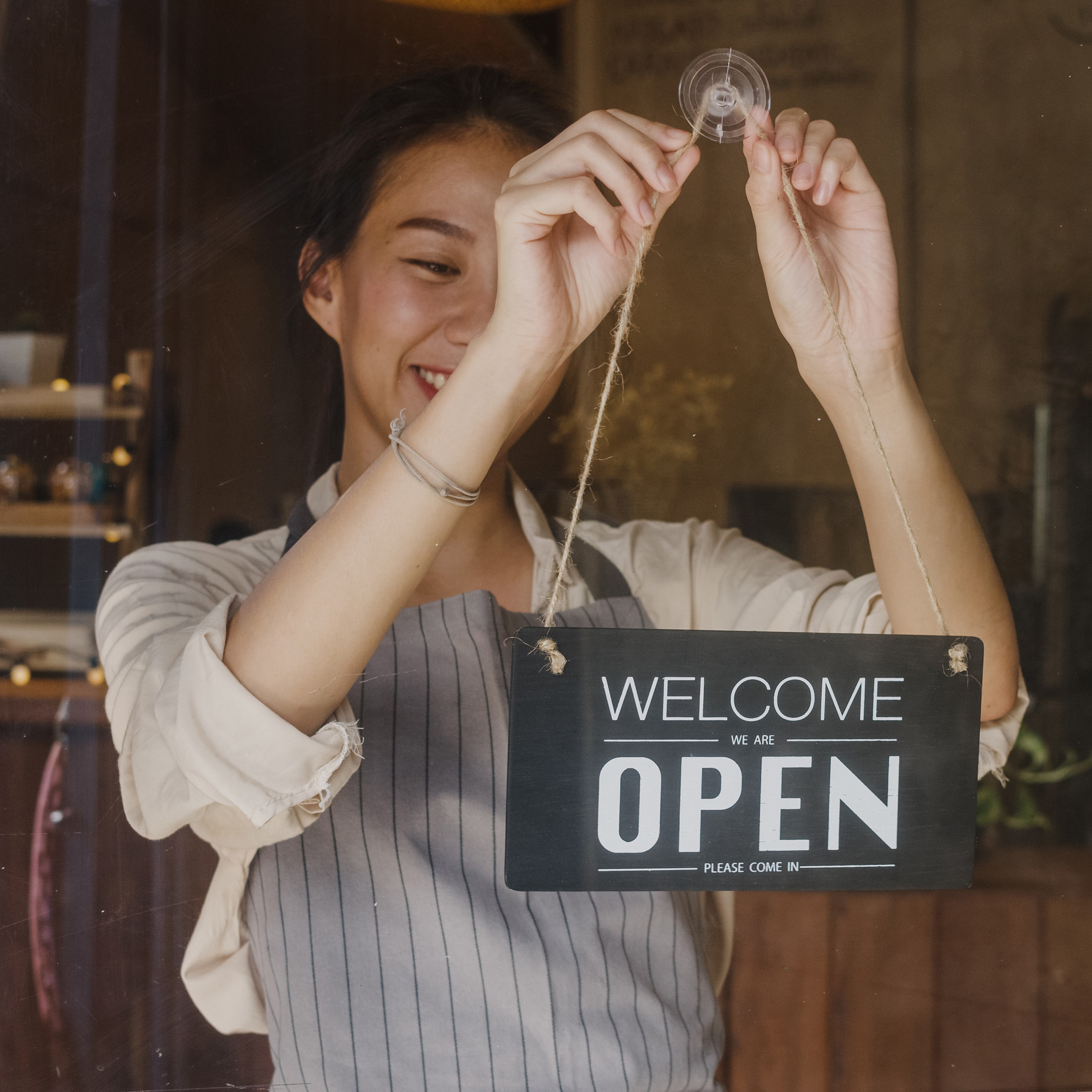 Young Asia Manager Girl Changing A Sign From Closed To Open Sign